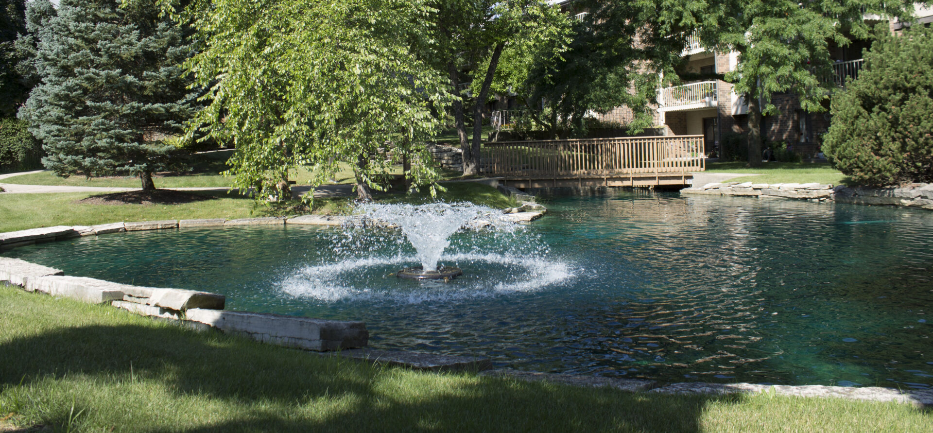 A fountain in a pond outside the independent living apartments at vmp milwaukee.