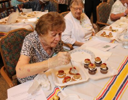 VMP West Allis Senior Community Club senior woman decorating her cupcakes in a Fun with Food class