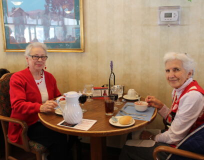 VMP West Allis Senior Community Club ladies smiling as they enjoy a luncheon, wearing red