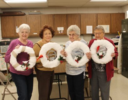 VMP Senior Community Club senior women holding up their wreaths they created in holiday craft class