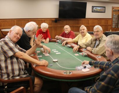 VMP West Allis Senior Community Club seniors playing poker around a poker table smiling at the camera